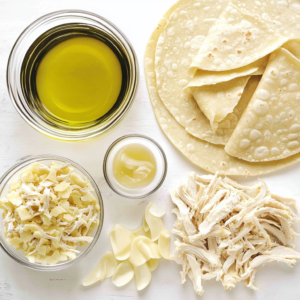 Ingredients for Flautas de Pollo laid out, including shredded chicken, tortillas, and spices.