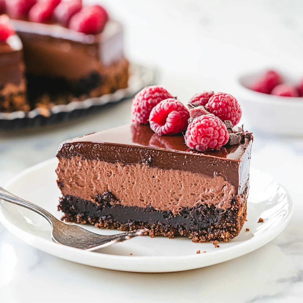 A rich and creamy chocolate cheese cheesecake on a white plate, topped with chocolate shavings.